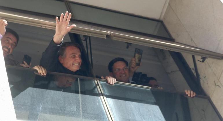 Ex-presidente Jair Bolsonaro acena de uma janela na sede do PL, no Brasil 21, em Brasília