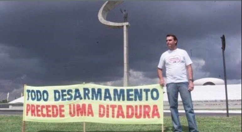 Ex-presidente Jair Bolsonaro ao lado de uma faixa com os dizeres: 'todo desarmamento precede uma ditadura'