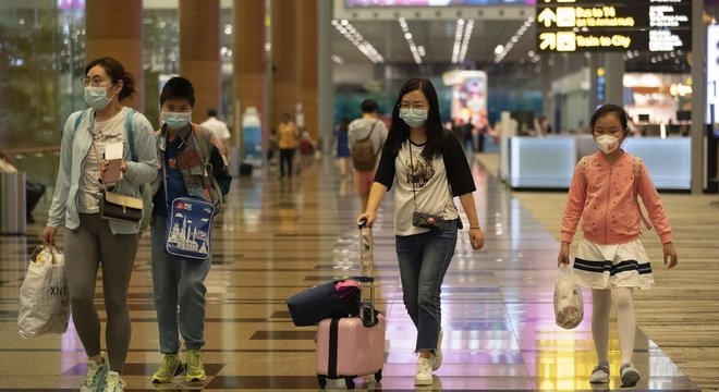 Passageiros em aeroporto de Cingapura; organismos internacionais como OMS se colocam contra medidas 'extremas' como fechamento de fronteiras e banimento de voos