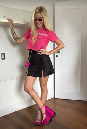 Na última quarta-feira (25), Karoline Lima também usou um look no estilo Barbie. Ela combinou minissaia preta de fendas laterais com cropped, sandália de salto plataforma, microbolsa transversal e óculos de sol