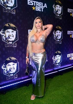 Um dos looks mais ousados e chamativos da noite foi o de Juju Ferrari. Ela elegeu uma combinação metalizada toda prata, composta de biquíni cortininha e saia longa de cintura baixíssima, com fenda lateral. Destaque para a body chain (corrente de corpo) na região da cintura, acessório queridinho das fashionstas. Sandálias transparentes e uma minibolsa preta completaram o figurino