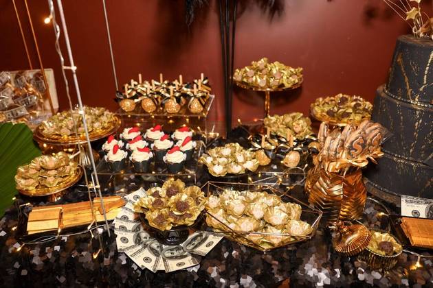 A mesa estava cheia de doces com embalagens douradas, entre mais dólares e barras de ouro