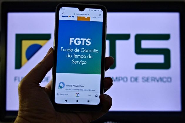  Vista de carteira de trabalho e de celular conectado ao Site da Caixa Econômica, na aba sobre FGTS no Rio de Janeiro (RJ), nesta quinta-feira (20). O STF deve começar hoje, julgamento que pode alterar a taxa de correção monetária do FGTS (Fundo de Garantia do Tempo de Serviço), favorecendo os trabalhadores