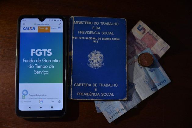 RJ - STF-JULGA-ALTERAR-TAXA-CORREÇÃO-MONETÁRIA-FGTS - GERAL - Vista de carteira de trabalho e de celular conectado ao Site da Caixa Econômica, na aba sobre FGTS no Rio de Janeiro (RJ), nesta quinta-feira (20). O STF deve começar hoje, julgamento que pode alterar a taxa de correção monetária do FGTS (Fundo de Garantia do Tempo de Serviço), favorecendo os trabalhadores. 