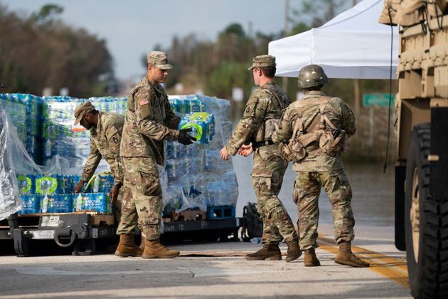 Homens do Exército americano entregam água potável na região inundada pelo rio Peace
