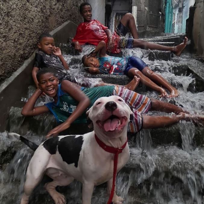 Bela e as crianças, que são todas vizinhas, posam para foto feliz 
na chuva