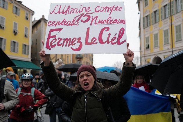 Mulher segura um cartaz que diz 'Ucrânia conta 15 usinas nucleares, feche o céu' durante uma manifestação contra a invasão militar da Rússia na Ucrânia, na cidade de Nice, na riviera francesa