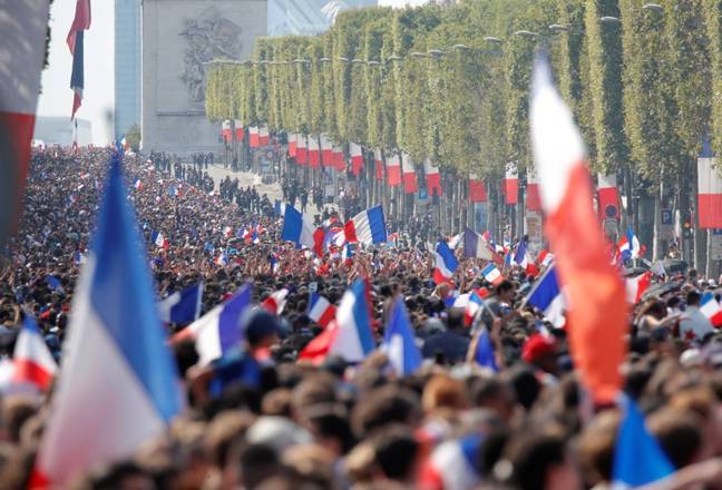 De outra perspectiva, os Campos Elísios hasteiam bandeiras da França por toda a parte, e a torcida, ainda esperando a chegada dos jogadores, já faz a festa em Paris.