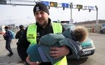 Um guarda polonês ajuda uma criança ucraniana a cruzar a fronteira entre os dois países neste sábado (26)