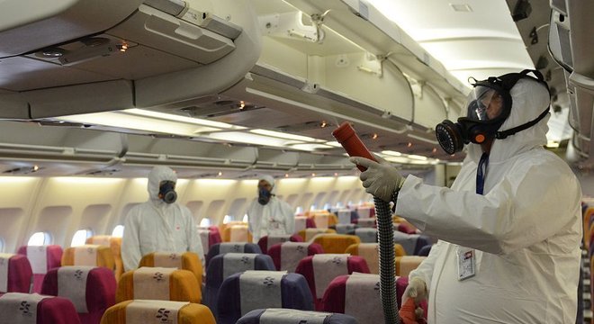 Funcionários aplicam solução antisséptica em avião na Tailândia, em 2015, como prevenção à síndrome respiratória Mers