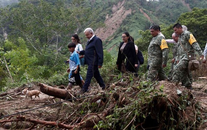 Centenas de turistas caminhavam com o que conseguiram salvar de seus pertences pela avenida Miguel Alemán, a principal da cidade, de acordo com essas mesmas imagens. Na foto, todo de azul, está Andrés Manuel López Obrador, presidente do México