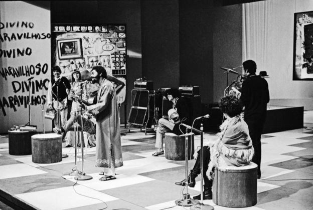 Gal Costa (sentada, de costas) com Caetano Veloso e Gilberto Gil na estreia do programa Divino e Maravilhoso, mostrando o movimento tropicalista na TV Tupi, em 1968