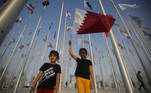 Crianças tiram fotos no Flag Plaza enquanto seguram bandeira do Catar, país sede da Copa do Mundo, em 5 de outubro