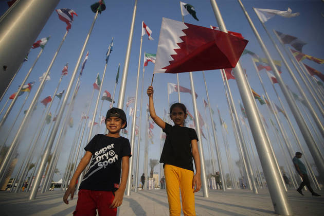 Crianças tiram fotos no Flag Plaza enquanto seguram bandeira do Catar, país sede da Copa do Mundo, em 5 de outubro