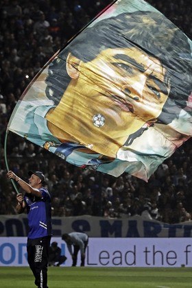 Um torcedor do Gimnasia y Esgrima agita uma bandeira com a imagem do ex-craque argentino Diego Maradona antes da partida do Torneio da Liga Profissional de Futebol Argentino 2022 no estádio Juan Carmelo Zerillo, na cidade de La Plata, Buenos Aires, em 6 de outubro