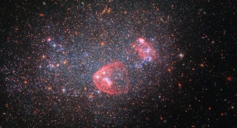 O telescópio espacial Hubble fez uma fotografia de um feixe de luzes conhecido como UGC 8091 ou GR 8. Ele é proveniente de uma galáxia anã irregular — ou seja, comparativamente pequena, de baixa massa e sem forma distinta ou uniforme