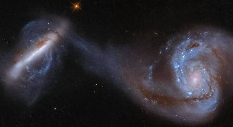 À medida que as galáxias NGC 3808A (direita) e NGC 3808B (esquerda) duelam, uma ponte cósmica de estrelas, feita de gás e poeira, estende-se por 75.000 anos-luz para uni-las