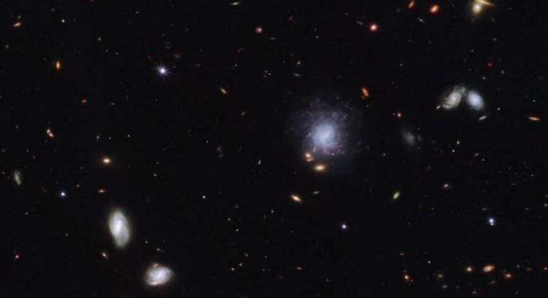 Esta imagem mostra a explosão de raios gama GRB 230307A, no canto esquerdo, e a galáxia a que ela pertencia mais ao centro. O GRB foi provavelmente alimentado pela fusão de duas estrelas de nêutrons, sendo 