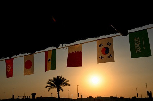 Bandeiras da Tunísia, Japão, Gana, Catar, Coreia do Sul e Arábia Saudita são retratadas ao pôr do sol no Souq Al-Wakrah em Doha, em 3 de novembro
