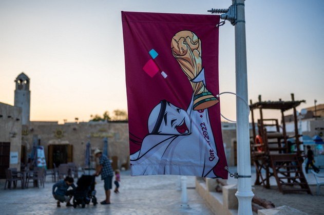 Pessoas passam por banners da Copa do Mundo da FIFA em uma praia em Doha em 3 de novembro de 2022, antes do torneio de futebol da Copa do Mundo da FIFA Catar 2022