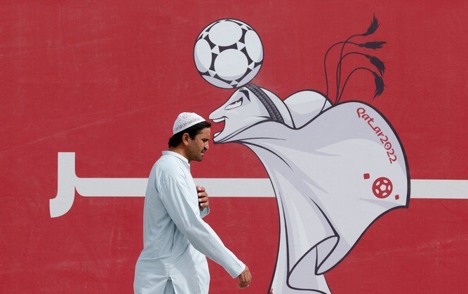 Um homem passa por um pôster do mascote La'eeb do Catar 2022, em Doha, em 9 de novembro