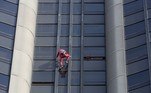 O alpinista francês de arranha-céus Alain Robert, conhecido como o Homem-Aranha francês, é observado por um bombeiro enquanto escala a Torre Montparnasse de 210 metros de altura, em Paris, em 12 de outubro