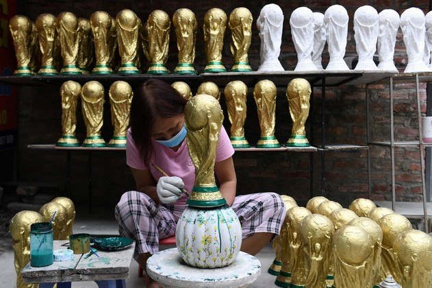 Uma trabalhadora pinta um modelo de gesso do troféu da Copa do Mundo da FIFA em uma oficina em Hanói em 16 de novembro, antes da Copa do Mundo