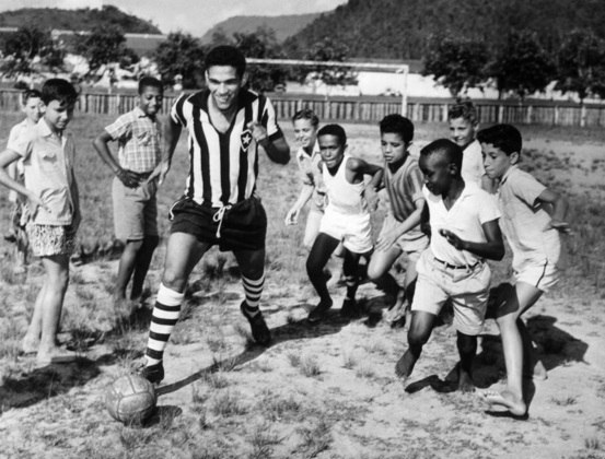 PAU GRANDE (BRASIL), 1958.- El jugador Garrincha, delantero de la selección brasileña de fútbol, juega con varios niños ataviado con la camiseta del club Botafogo, durante una visita a su tierra natal, Pau Grande. EFE/Manchete/jgb

