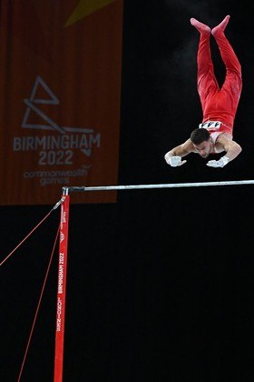 O inglês Giarnni Regini-Moran compete na barra horizontal durante a final da equipe masculina de ginástica artística na Arena Birmingham, em Birmingham, no primeiro dia dos Jogos da Commonwealth em Birmingham, centro da Inglaterra, em 29 de julho