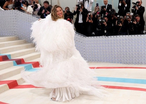 Gisele Bündchen, chega ao Met Gala usando um look com plumas branco e luxuoso.
