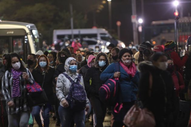 Pessoas paradas esperando ônibus em estação na zona leste de São Paulo