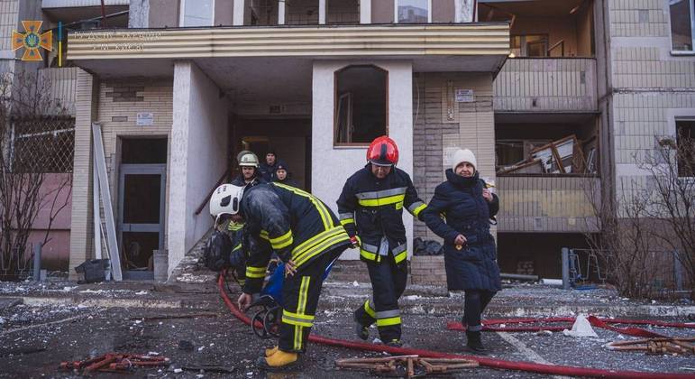 Equipes de resgate ajudam mulher a sair de prédio residencial atingido por ataque aéreo em Kiev