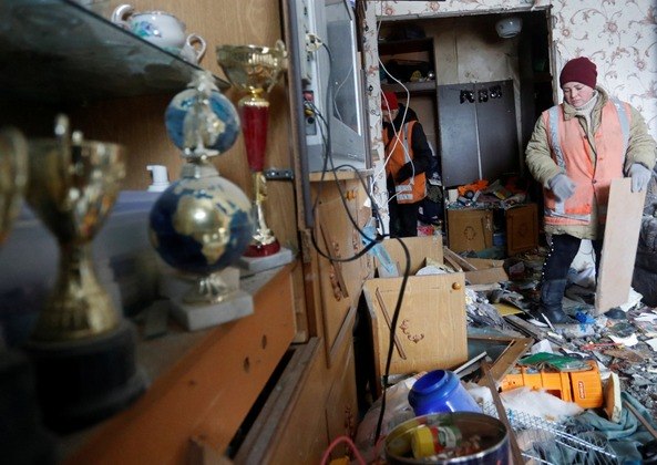 Funcionários municipais removem detritos de um apartamento, que moradores disseram ter sido danificado por bombardeios recentes, na cidade controlada pelos separatistas de Yasynuvata (Yasinovataya) na região de Donetsk, Ucrânia