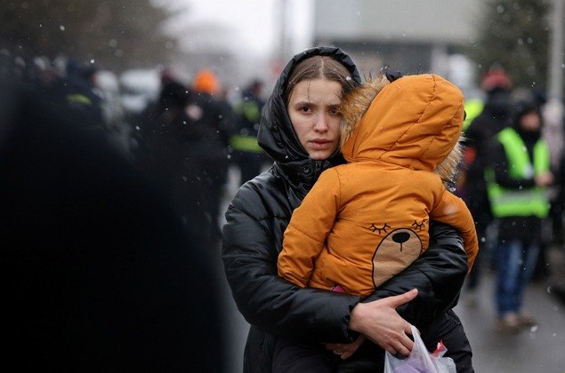 Uma mulher carrega uma criança depois de fugir da invasão da Ucrânia pela Rússia, na fronteira em Siret, Romênia Uma mulher carrega uma criança depois de fugir da invasão da Ucrânia pela Rússia, na fronteira em Siret, Romênia