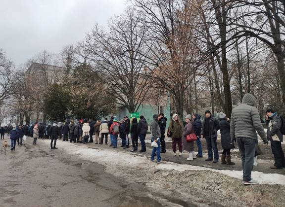 Moradores locais fazem fila para receber comida na área de um hospital em Kharkiv, enquanto a invasão russa da Ucrânia continua