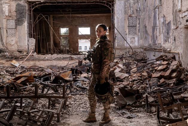 Nos arredores de Bajmut, na Ucrânia, na linha de frente de um pelotão de artilharia, uma comandante de 32 anos chacoalhava de um lado para o outro no banco do passageiro de um Lada destruído, enquanto outro soldado dirigia o carro em meio a uma floresta densa, às vezes até derrubando árvores jovens. Quando chegaram ao destino, uma pequena vila a pouco mais de três quilômetros das linhas russas, só restavam casas destruídas, com os telhados arruinados visíveis à luz do luar