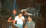 Apenas em 1997, cinco anos após a morte de Daniella Perez, é que Guilherme de Pádua e sua então mulher, Paula Thomaz, começaram a ser julgados. Na foto, Guilherme em seu julgamento, sentado ao lado de dois policiais. Ele foi condenado a 19 anos de prisão, dos quais cumpriu apenas 7. O ex-ator morreu na noite deste domingo (6) em casa, em Belo Horizonte. A causa foi um infarto fulminante