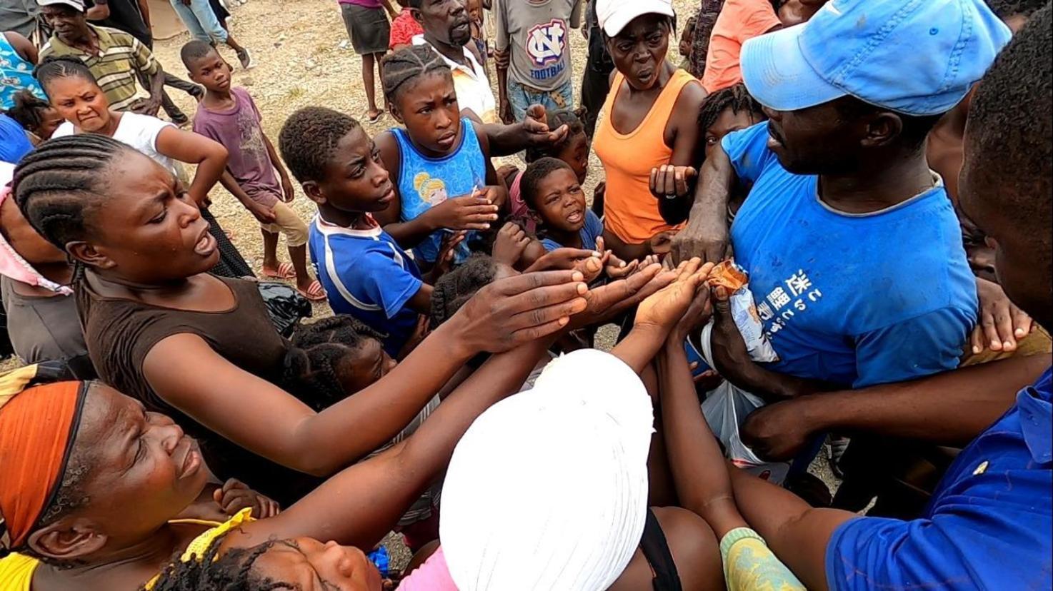 Crianças e mulheres disputam um pirulito em Jérémie, no Sudoeste do Haiti (RecordTV)