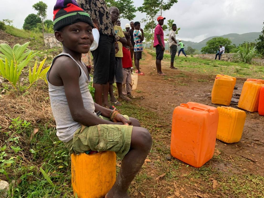 Menino espera sentado sua vez de pegar água em Jérémie (RecordTV)