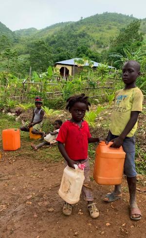 Menino e menina aguardam sua vez para pegar água em fonte de Jérémie (RecordTV)