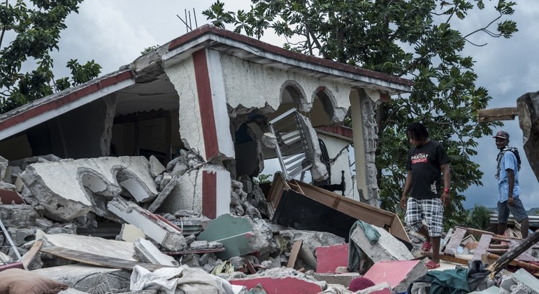 Pessoas vasculham destroços de casas destruídas pelo terremoto em Camp Perrin
