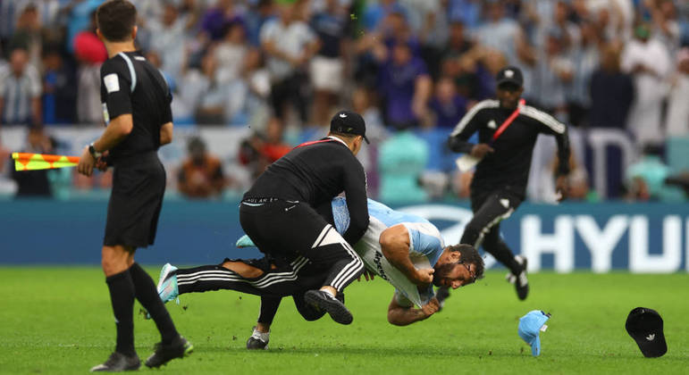 Segurança derrubam um invasor de campo no estádio Lusail