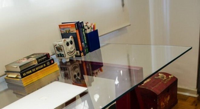 Home office com mesa de vidro e cadeira de madeira