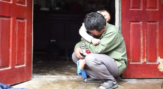 Le Minh Tuan abraça seu neto. Ele espera que seu filho não esteja entre os mortos