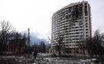 Homem caminha em frente a prédio residencial destruído após bombardeio próximo a Chernobyl