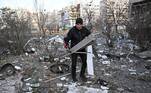 Homem carrega destroços após casas serem atacadas por mísseis em Kiev