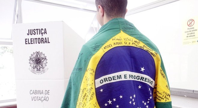 Homem envolvo em uma bandeira do Brasil se dirige à cabina de votação, em Belo Horizonte, Minas Gerais Em 16 anos, votação do PT cai quase pela metade no Sudeste