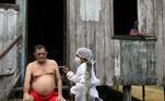 Lino Cavalcante Mota é vacinado por profissional de saúde na porta de sua casa de palafita