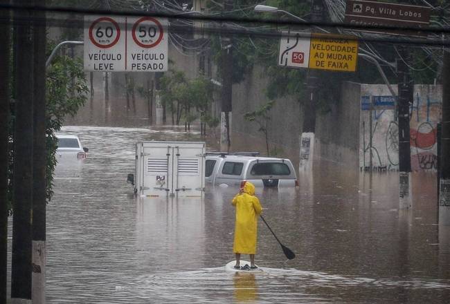 Homem usa stand up paddle para socorrer pessoas ilhadas pela enchente próximo à Ponte do Jaguaré