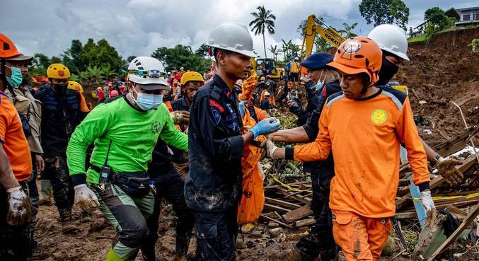 Equipe de resgate carrega corpo encontrado nos escombros da vila de Cugenang